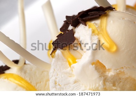Vanilla ice cream drizzled with honey and topped with dark chocolate flakes, close up view