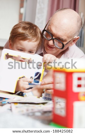 Grandfather helping  his little grandson to solve puzzle. Happy family time