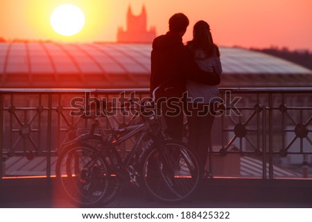 Young couple embracing and enjoying beautiful sundown in the city from the viewing point