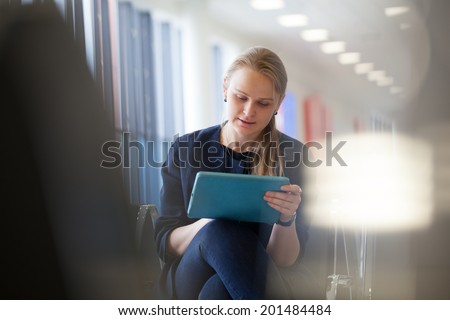 Young woman using tablet PC the waiting room of the station or airport