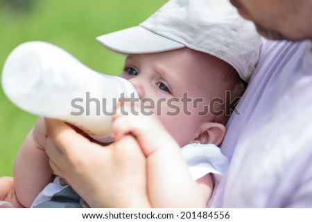 Man bottle feeding baby in his arms