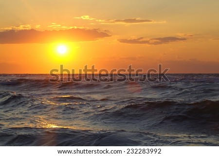Golden sunset over wavy sea. Rough water sparkling in the evening sunlight