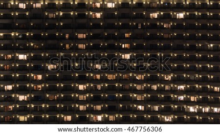 Facade of highrise apartment block with balconies. Electric lights in some windows. Housing in Bangkok, Thailand