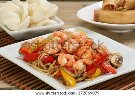 dish of prawn chow mein with crackers and spring rolls