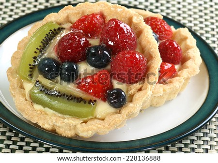 two mixed fruit tarts on a small plate
