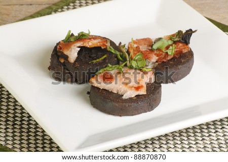 three pieced of grilled black pudding bacon and garnish
