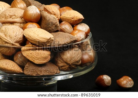 glass bowl filled with mixed nuts on a black background