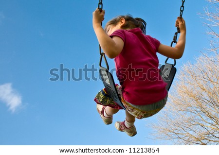 girl swings high into a blue sky with copyspace
