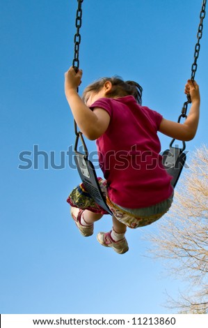 girl swings high into a blue sky vertical