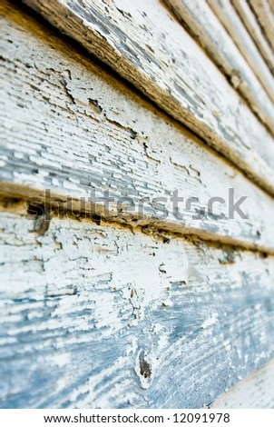 selective focus detail of cracking and peeling paint on ancient wood siding background