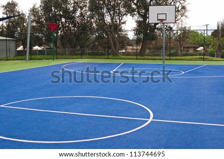 Center of basketball in bright green and blue, synthetic grass carpet surface with white lines and training basket