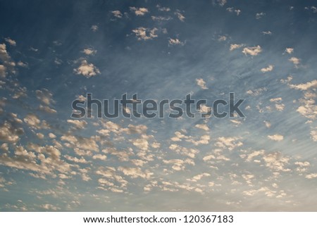 Fluffy small clouds with strong wind and traces in higher level clouds in background win sunlight of rising sun