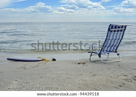 Blue beach chair and boogie board on sandy beach with clean water at Port Philip bay in Victoria, Australia