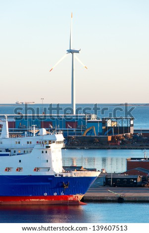 Cargo freight ship at shipyard and wind electric generator on background