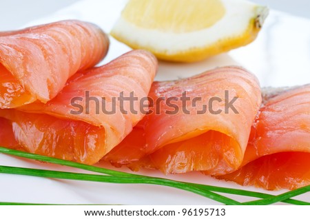 Close up smoked salmon pieces with lemon and chives