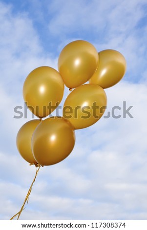 A bunch of flying golden balloons on the beautiful sky background