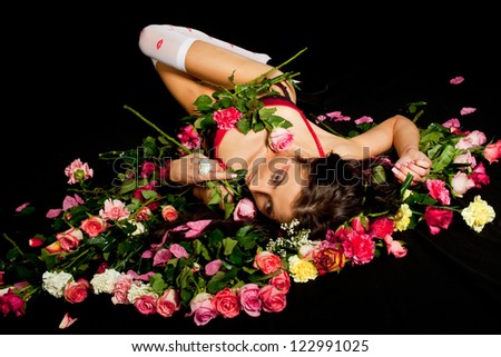 Young sexy girl wearing red lingerie posing laying on flowers. Studio low key shot