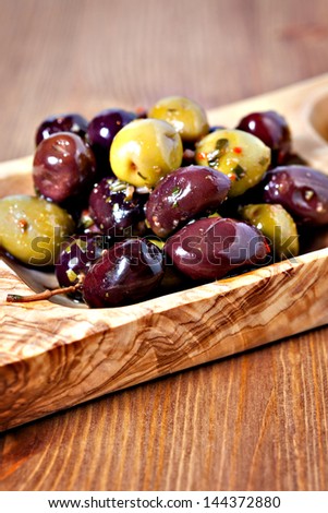 Closeup of mixed marinated olives in olive tree dish on wooden table