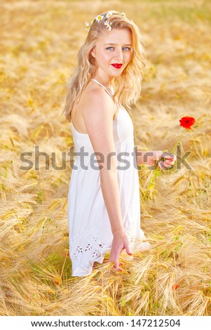 Portrait of pretty young woman at wheat field, a girl against golden wheat background expressing calmness emotions