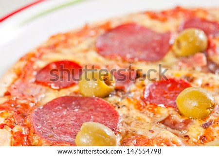 Macro of bacon and pepperoni pizza with green olives. More food photographs in my portfolio.