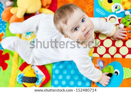 Closeup of happy six months baby boy crawling on colorful playmat