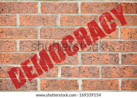 Red DEMOCRACY inscription on brick wall surface pattern as a wallpaper concept for designers background applying
