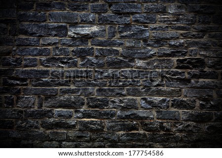 Dark brick-wall surface pattern as a wallpaper concept for designers background applying