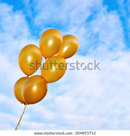 Bunch of flying inflatable golden balloons on the beautiful sky background