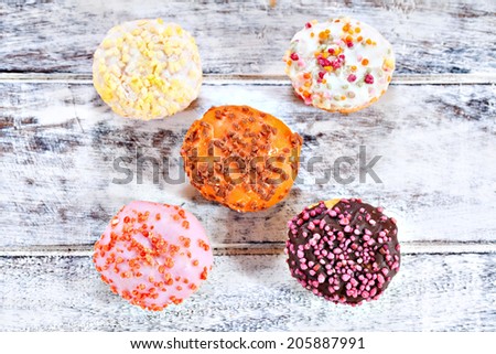 Mixed donuts with strawberry, chocolate, orange, lemon and vanilla flavor glaze on white wooden table background