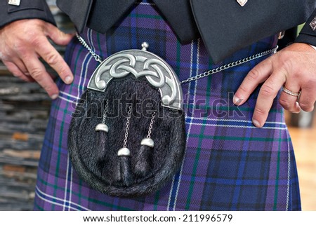 Closeup of traditional Scottish male ceremonial outfit. Man wearing blue tartan  kilt with beautiful fur and silver sporran.