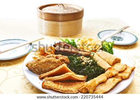 Assorted traditional chinese meal with plates, chopsticks and bamboo steamer on the table. Close-up