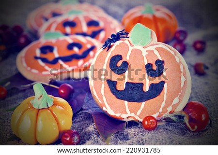 Stylized Halloween decor pumpkin cookies and assorted pumpkins. Popular American event party decorative dessert idea.