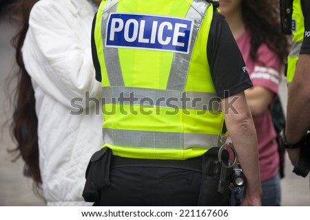 Police officers on duty. Daytime in public place outdoors. Back view