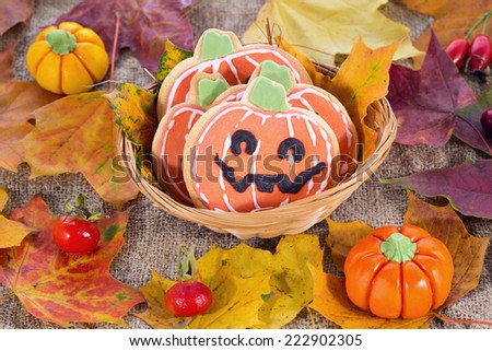 Closeup of Halloween decor pumpkin cookies and assorted pumpkins. Popular American event party decorative dessert idea.