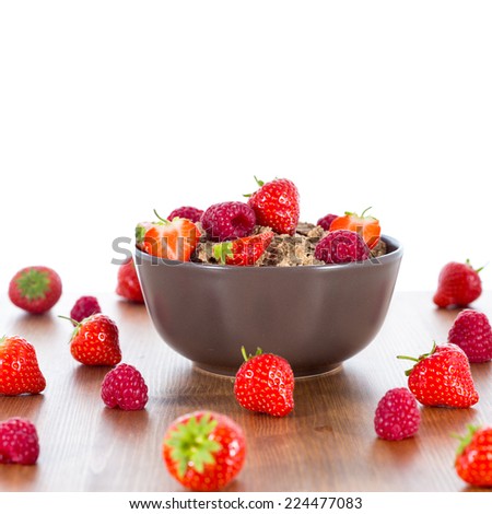 Bran flakes with fresh raspberries and strawberries on wooden table. Healthy eating choice concept