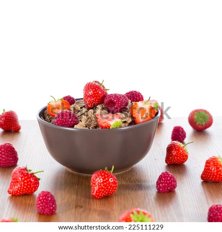Bran flakes with fresh raspberries and strawberries on wooden table. Healthy eating choice concept. Isolated on white background