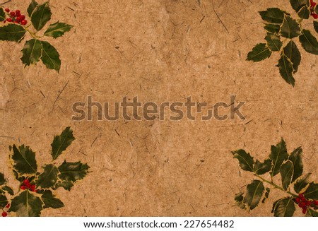 Holly leaf sprigs with red berries forming an abstract border on old textured paper. Vintage grunge stylized