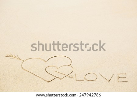 Inscription of Love with two hearts on wet beach sand. Concept of celebrating the St. Valentine\'s day at some exotic place