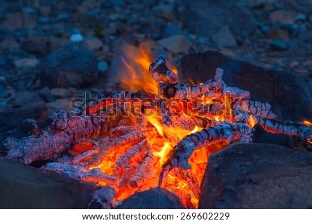 Classic camping campfire in rock fire ring at dusk closeup