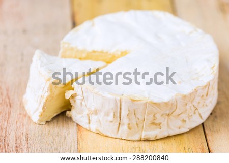 Camembert cheese with cut wedge and vintage knife on wooden table