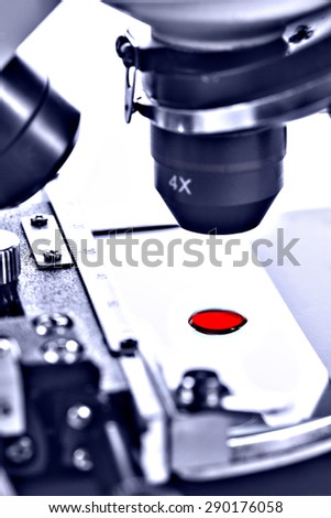 Blood drop sample on test glass plate under microscope lens. Medical laboratory equipment.