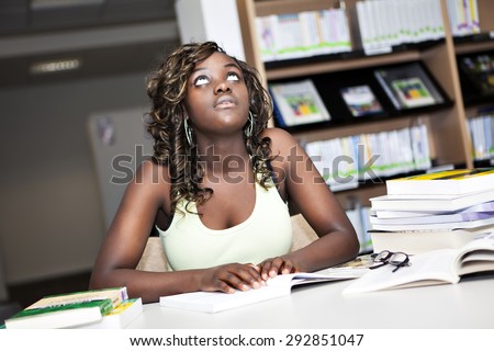 Back to School. Pretty teenage black african college student girl studying and reading a book in college library