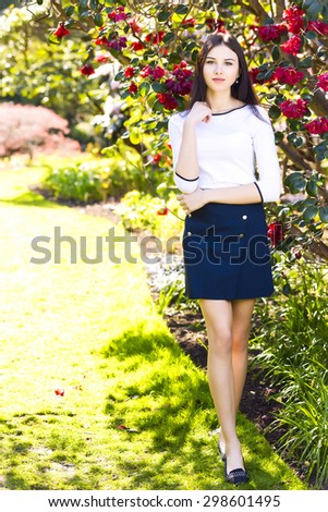 Young beautiful tall woman with long straight dark hair posing at spring garden