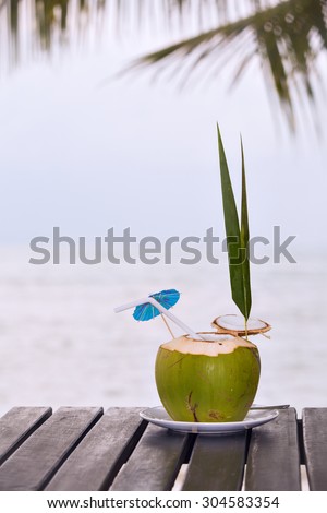 Coconut water drink served in coconut with drinking straw on the beach