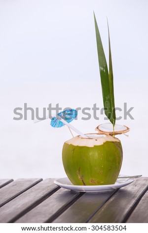 Coconut water drink served in coconut with drinking straw on the beach