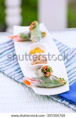 Vietnamese vegetable spring rolls served with walnut pate and mango sauce on a plate. Oriental vegetarian food, healthy eating choice