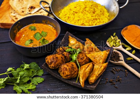 Indian pilau rice in balti dish served with chicken tikka masala curry, plain naan bread, vegetable samosas, and onion bhajis