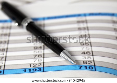 A pen lays on some Financial Analysis data report. Close-up