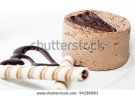 Chocolate mousse on plate decorated with two cookie sticks. On white plate