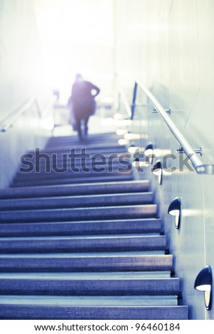Some person walks up concrete stairs to toward the light at the top. Concept of success stairs.